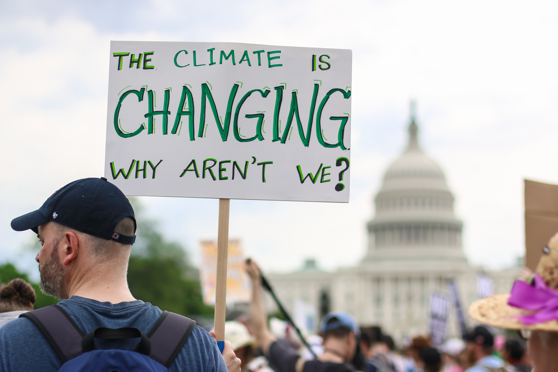 Guy holding a sign that says The Climate is Changing, why aren't we?
